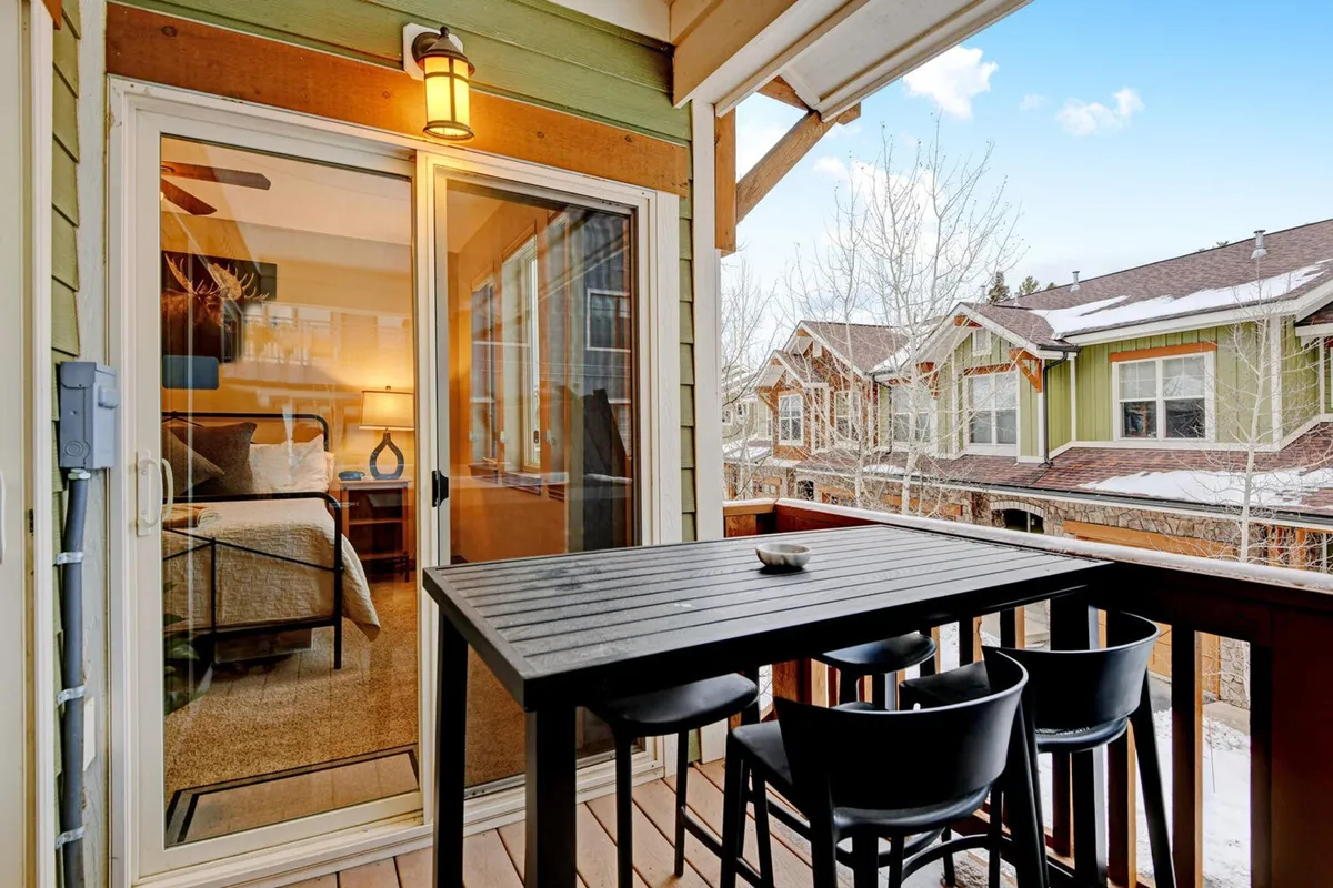 This outdoor scene highlights a balcony or patio with an outdoor dining table, surrounded by other buildings and filled with natural light. The space is ideal for sunset dinners, morning coffee, or relaxing after a day on the trails—activities that can include your dog.